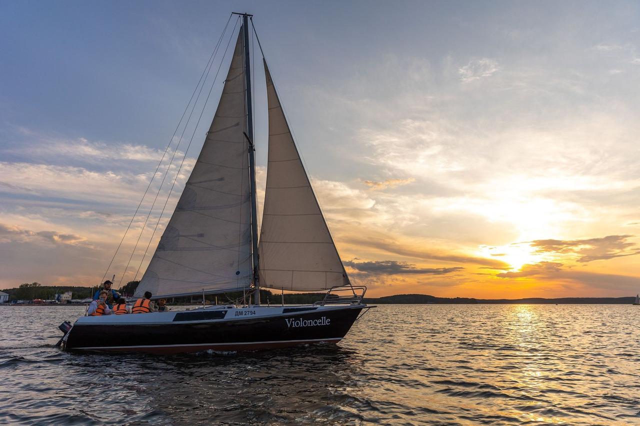 Un viaje en grupo de WeRoad en velero, navegando por el agua bajo una vibrante puesta de sol.