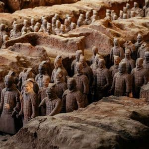 File di statue di guerrieri di terracotta in formazione in una fossa archeologica scavata.