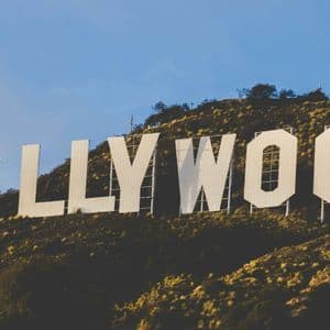 La grande insegna bianca di Hollywood si trova su una collina erbosa sotto un cielo azzurro e limpido.