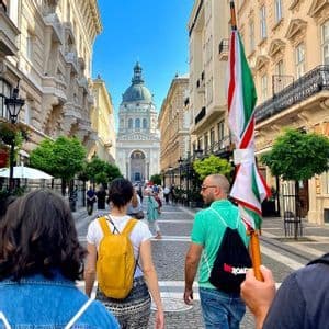 Un gruppo WeRoad in cammino lungo un'ampia strada cittadina, verso una grande basilica a cupola, sotto un cielo limpido e azzurro.