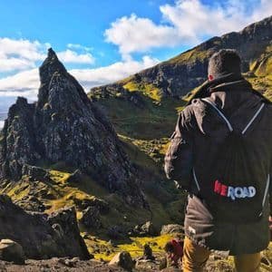 Ein Reisender auf einer WeRoad Gruppenreise, von hinten gesehen, blickt auf eine zerklüftete Berglandschaft mit einer markanten Felsnadel.