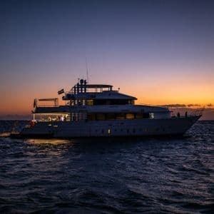 A WeRoad group trip on an illuminated yacht cruising on the open sea during a colorful sunset.