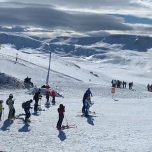 Un viaggio di gruppo WeRoad su una pista da sci innevata, con vista panoramica su montagne coperte di neve sotto un cielo parzialmente nuvoloso.
