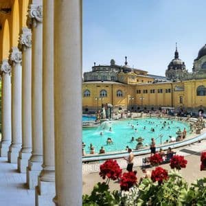 The outdoor pools of the Szechenyi thermal baths in Budapest framed by flowers.