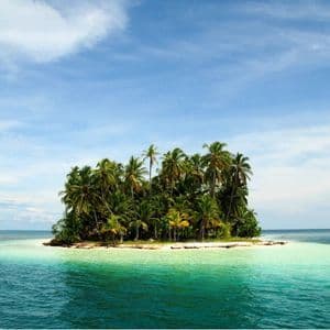 Una pequeña isla tropical llena de palmeras está rodeada por un océano turquesa y azul profundo bajo un cielo parcialmente nublado.