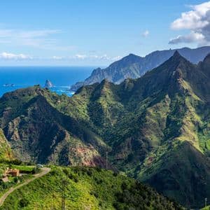 Vista panoramica su una catena montuosa aspra e verde che digrada nell'oceano blu in una giornata di sole.