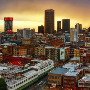 Un paysage urbain étendu mêlant immeubles bas et grat-ciels sous un ciel de coucher de soleil doré.