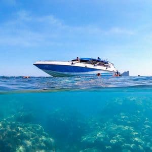 Una vista split-shot di un motoscafo in superficie e di un gruppo WeRoad che fa snorkeling su una barriera corallina.