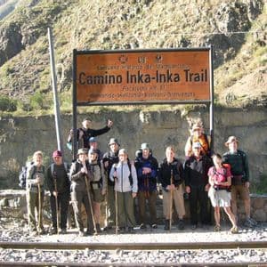 A WeRoad group trip in hiking gear poses for a photo in front of the 'Camino Inka-Inka Trail' sign.