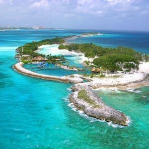 Una vista aerea di una piccola isola tropicale con spiagge di sabbia bianca, vegetazione lussureggiante e una piccola laguna, circondata da acqua turchese.