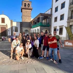 Un gruppo WeRoad in posa per una foto in una soleggiata piazza cittadina, con un campanile in pietra ed edifici storici sullo sfondo.