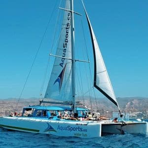 Un viaje en grupo de WeRoad con personas relajándose en la cubierta de un catamarán mientras navega por el mar azul bajo un cielo despejado.