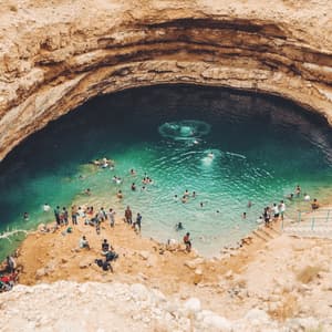 A WeRoad group trip swimming and relaxing in a large natural sinkhole with turquoise water, viewed from above.