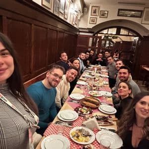Eine WeRoad-Gruppe sitzt lächelnd für ein Foto an einem langen Esstisch in einem Restaurant.