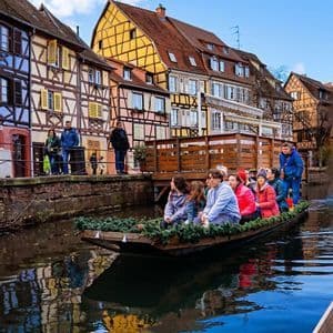 Un viaje en grupo de WeRoad hace un recorrido en barco por un canal, con coloridos edificios de entramado de madera reflejados en el agua.