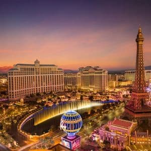 Una vista aerea della Las Vegas Strip al tramonto, con la replica illuminata della Torre Eiffel e le fontane del Bellagio.