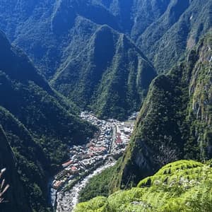 Vista a gran altura de un pueblo enclavado en un valle profundo, rodeado de montañas empinadas cubiertas de denso bosque verde.