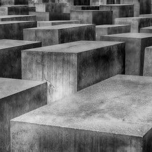 Una fotografía en primer plano, en blanco y negro, que muestra numerosos bloques rectangulares de hormigón de diferentes alturas dispuestos en una densa cuadrícula.