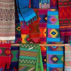 Una collezione di tessuti colorati intrecciati con intricati motivi geometrici e bordi frangiati esposti.