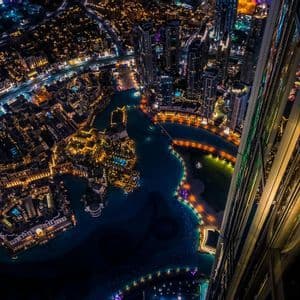Vista dall'alto da un grattacielo su una città illuminata con corsi d'acqua e ponti di notte.