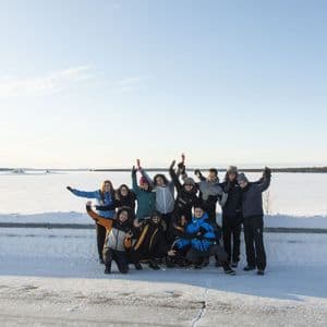 A WeRoad group trip in winter clothing posing for a photo in a vast, snowy landscape under a clear sky.