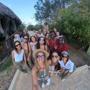 Un gruppo WeRoad posa per un selfie grandangolare con persone del posto su un sentiero in pietra all'aperto.