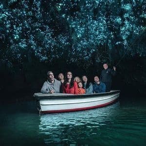 Eine WeRoad-Gruppenreise im Boot bestaunt die biolumineszenten Glühwürmchen an der Decke einer dunklen Höhle.