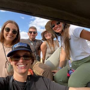 Un voyage de groupe WeRoad souriant pour un selfie à l'intérieur d'un véhicule de safari sous un ciel ensoleillé.