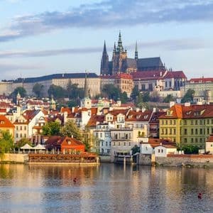 Colourful houses along the Vltava river with Prague Castle rising behind them.