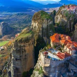 Una veduta aerea di antichi monasteri con tetti in tegole rosse costruiti su alti pilastri rocciosi in una valle montana.
