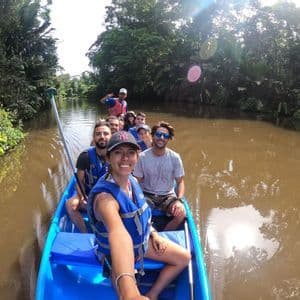 Una donna si scatta un selfie con il suo gruppo WeRoad in una canoa blu su un fiume in una giungla lussureggiante.