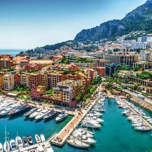 Vista aerea di un porto ricco di yacht e barche a vela, con una vivace città costruita sulla collina a picco sul mare.