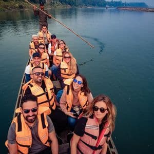 Eine WeRoad-Reisegruppe mit orangefarbenen Schwimmwesten sitzt in einem langen Holzboot, das von einem Guide einen Fluss entlang gestakt wird.