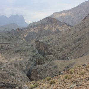 Un extenso y rocoso paisaje montañoso con un profundo cañón que lo atraviesa bajo un cielo nublado.