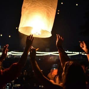 Un viaggio di gruppo WeRoad rilascia una grande lanterna di carta luminosa nel cielo notturno tra altre lanterne fluttuanti.
