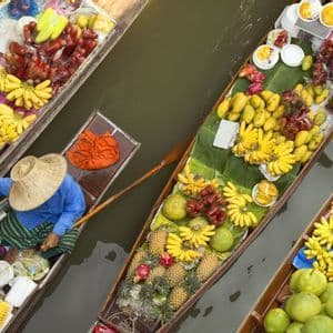 Vue aérienne de bateaux remplis de fruits tropicaux colorés tels que des bananes et des ananas, dans un marché flottant.