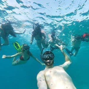 Un gruppo in viaggio con WeRoad scatta un selfie mentre fa snorkeling insieme sotto la superficie dell'acqua.