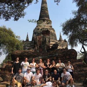Un viaje en grupo de WeRoad posando para una foto frente a un antiguo templo de ladrillo con una alta estupa bajo un cielo despejado.