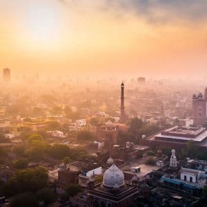 Una vista aérea de una ciudad histórica con una gran mezquita y minaretes durante un amanecer brumoso y dorado.