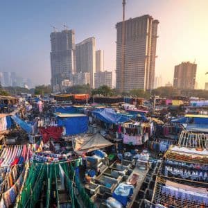 Vista aérea de una extensa lavandería al aire libre con ropa secándose en tendederos, con rascacielos modernos de la ciudad de fondo.