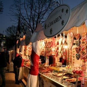 Una luminosa bancarella di dolci in un mercato notturno, con cuori di pan di zenzero e caramelle esposte.