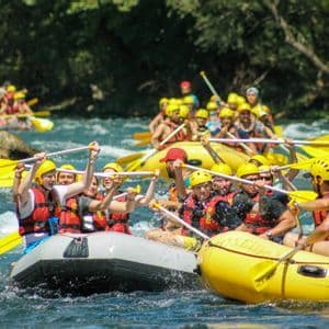 Un viaggio di gruppo WeRoad su gommoni gialli lungo un fiume, esultando con le pagaie alzate in aria.