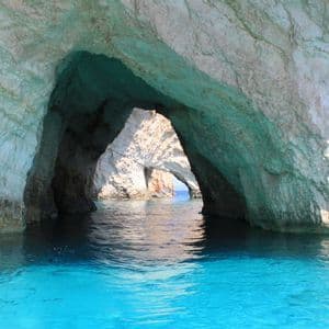 Una vista dall'acqua di grandi formazioni rocciose che creano archi naturali e grotte marine in acque turchesi brillanti.