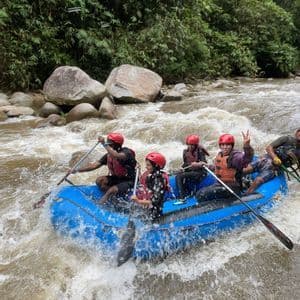 Un voyage en groupe WeRoad: rafting en eaux vives sur une rivière agitée, à bord d'un radeau gonflable bleu au milieu d'une jungle luxuriante.