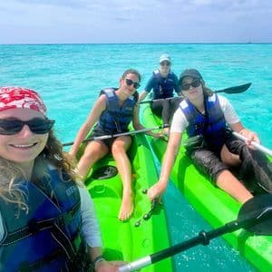 Vier Frauen einer WeRoad Gruppe machen ein Selfie beim Kajakfahren in klarem, türkisfarbenem Wasser.