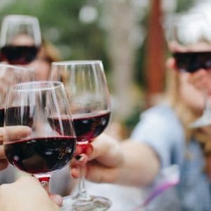 Brindisi di gruppo WeRoad con calici di vino rosso in primo piano.