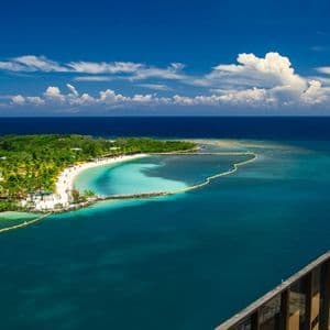 Eine Luftaufnahme einer tropischen Insel mit einem weißen Sandstrand und einer türkisfarbenen Bucht, umgeben vom tiefblauen Ozean.