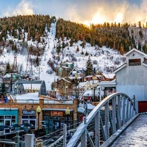 Un puente domina el pueblo en la estación de esquí de Park City Mountain, con pistas cubiertas de nieve y telesillas visibles al amanecer.