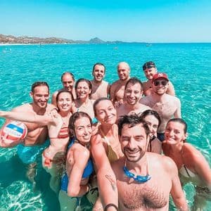 A WeRoad group trip smiling and taking a selfie while standing together in clear turquoise water.