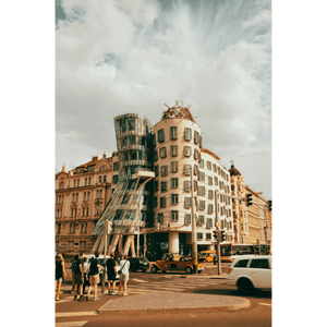 Un edificio dall'architettura decostruttivista, con una torre di vetro, si trova su una strada cittadina trafficata.